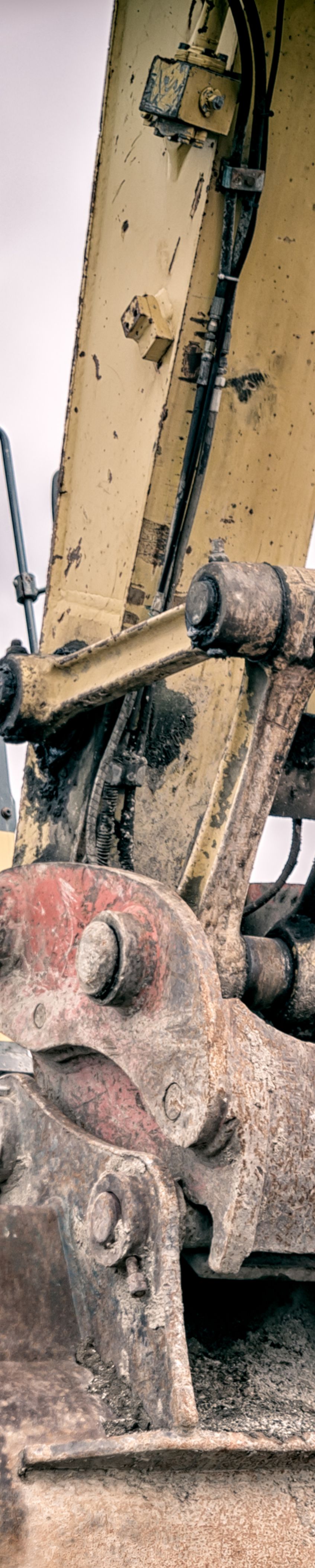 Image of a man with his hands crossed and smiling standing in front of an excavator