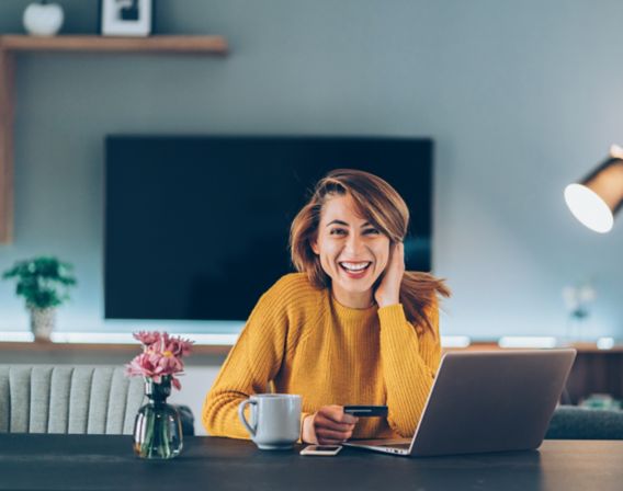 The girl in a yellow sweater sitting at a computer and smiling into the camera