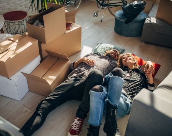 Woman and man lying on the floor with moving boxes