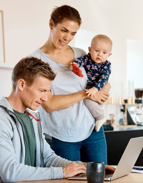 Bilde av en ung familie som ser på en datamaskin 