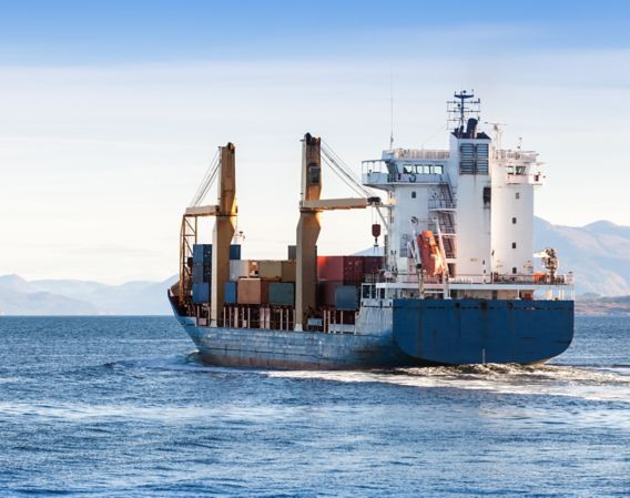Bilde av et blått lasteskip på havet med en del containere ombord 