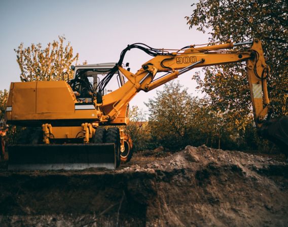 Bilde av en gravemaskin som graver en grøft på høsten