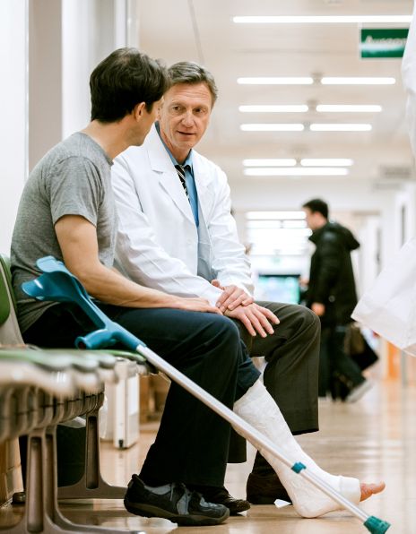 Bilde av en mannlig lege og en mannlig pasient med krykker på sykehus