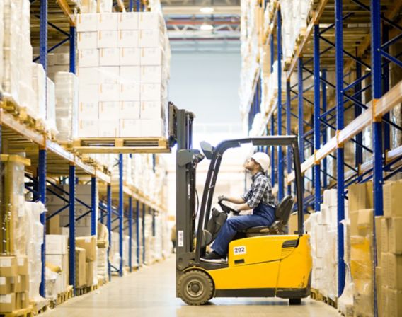 Image of a forklift with a worker lifting a pallet with boxes in a warehouse