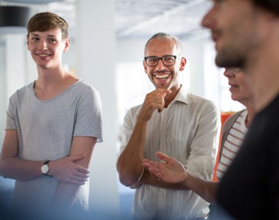 Bilde av fire smilende kollegaer i et møte 
