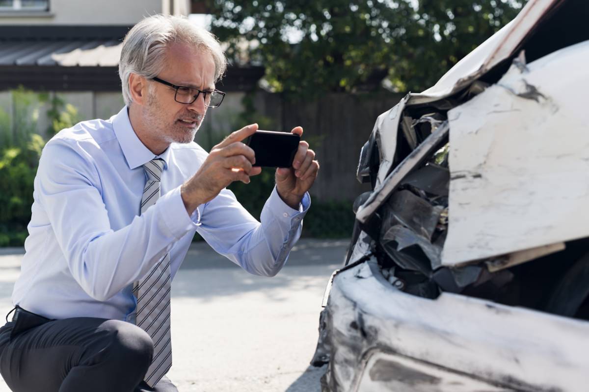 A man taking a picture of damage to a car