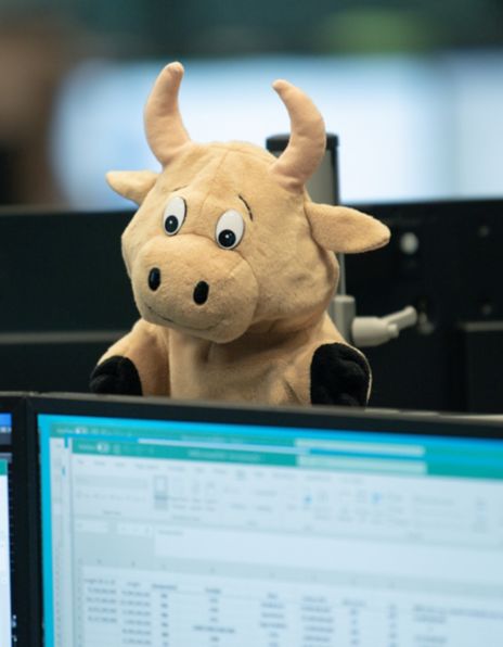 A finger puppet of a bull hanging on a computer with graphs