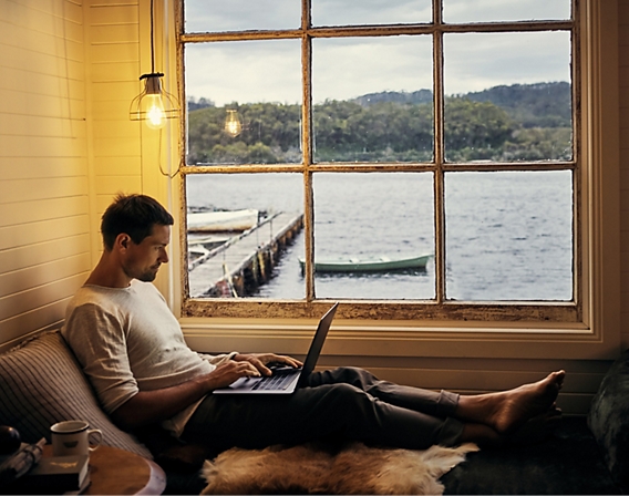 Man with computer in a oceanside cabin