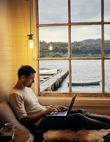 Man with computer in an oceanside cabin
