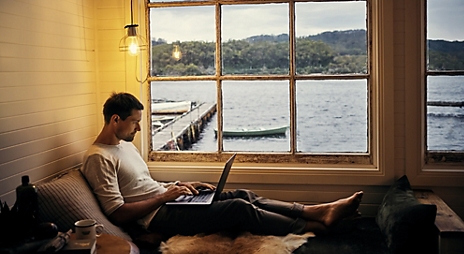 Man with computer in a oceanside cabin