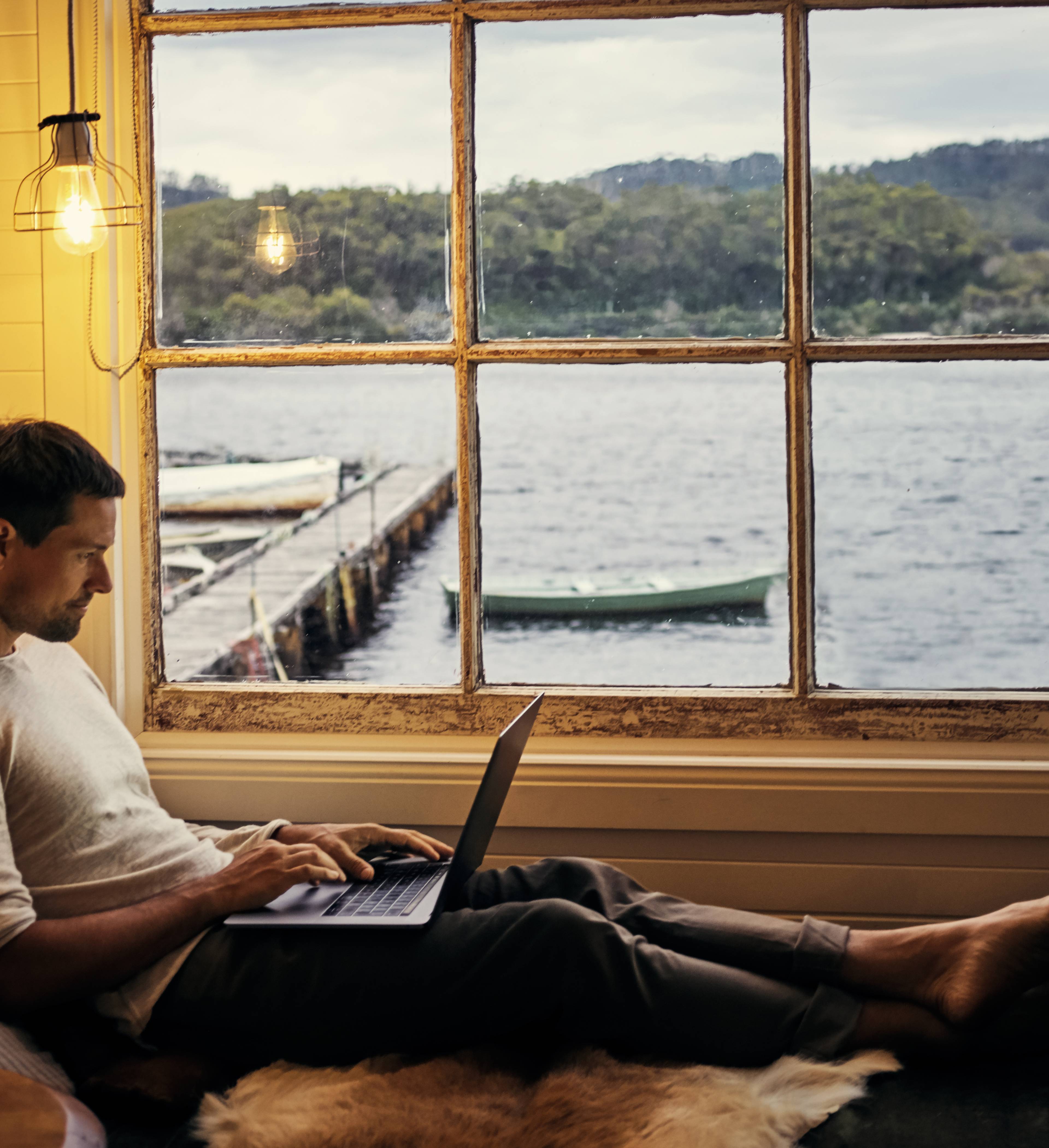 Mann med PC på sjøhytte