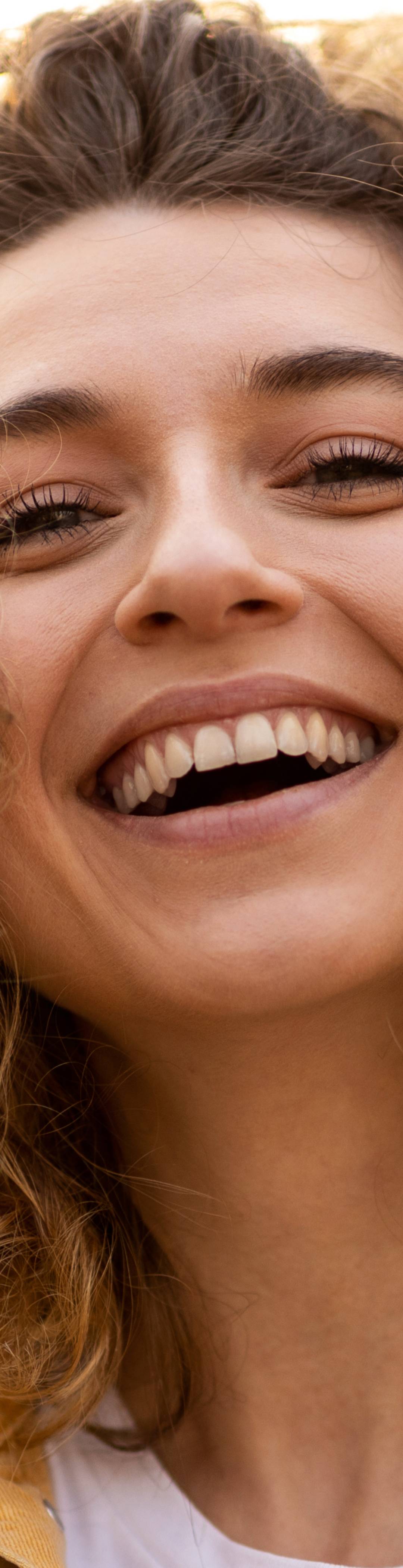 Ung dame med krøllete hår som smiler over best i test-forsikring.