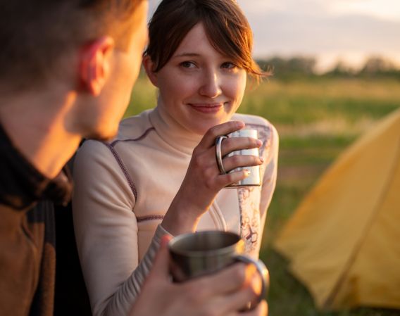 Par som drikker kaffe utenfor telt