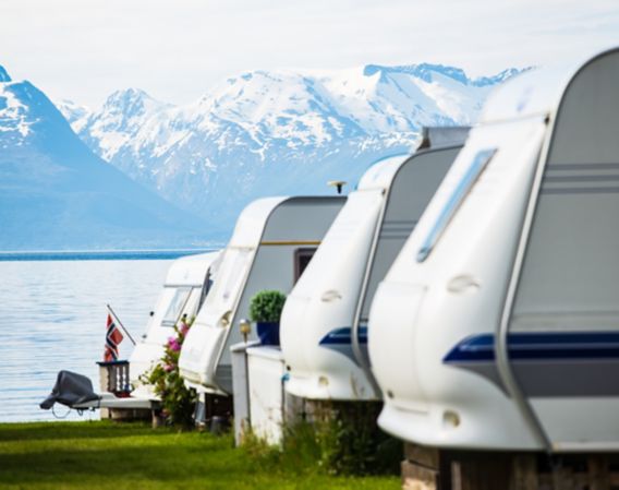 Caravans parked in a row by a fjord.