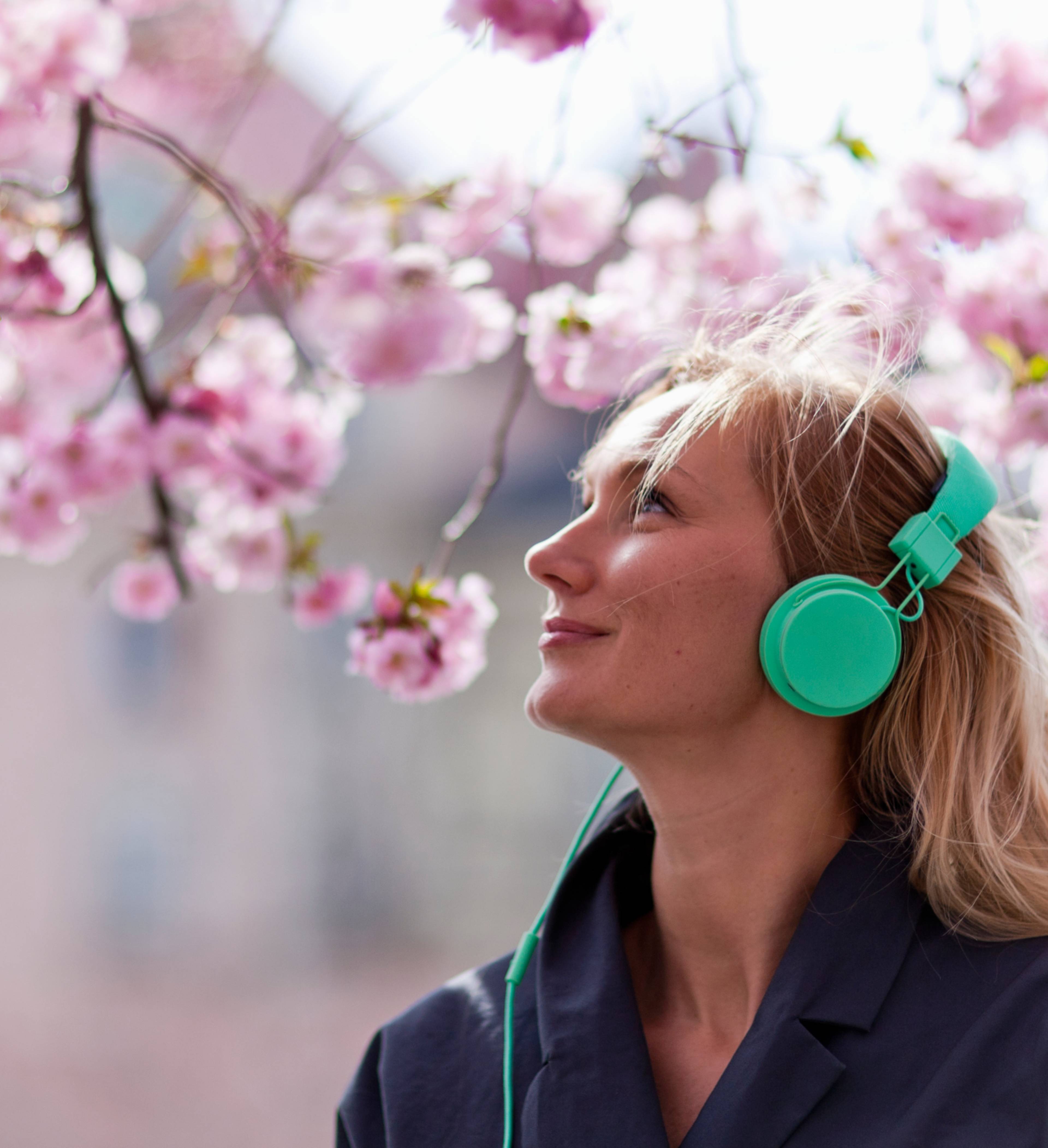 Kvinne med høretelefoner under et kirsebærtre