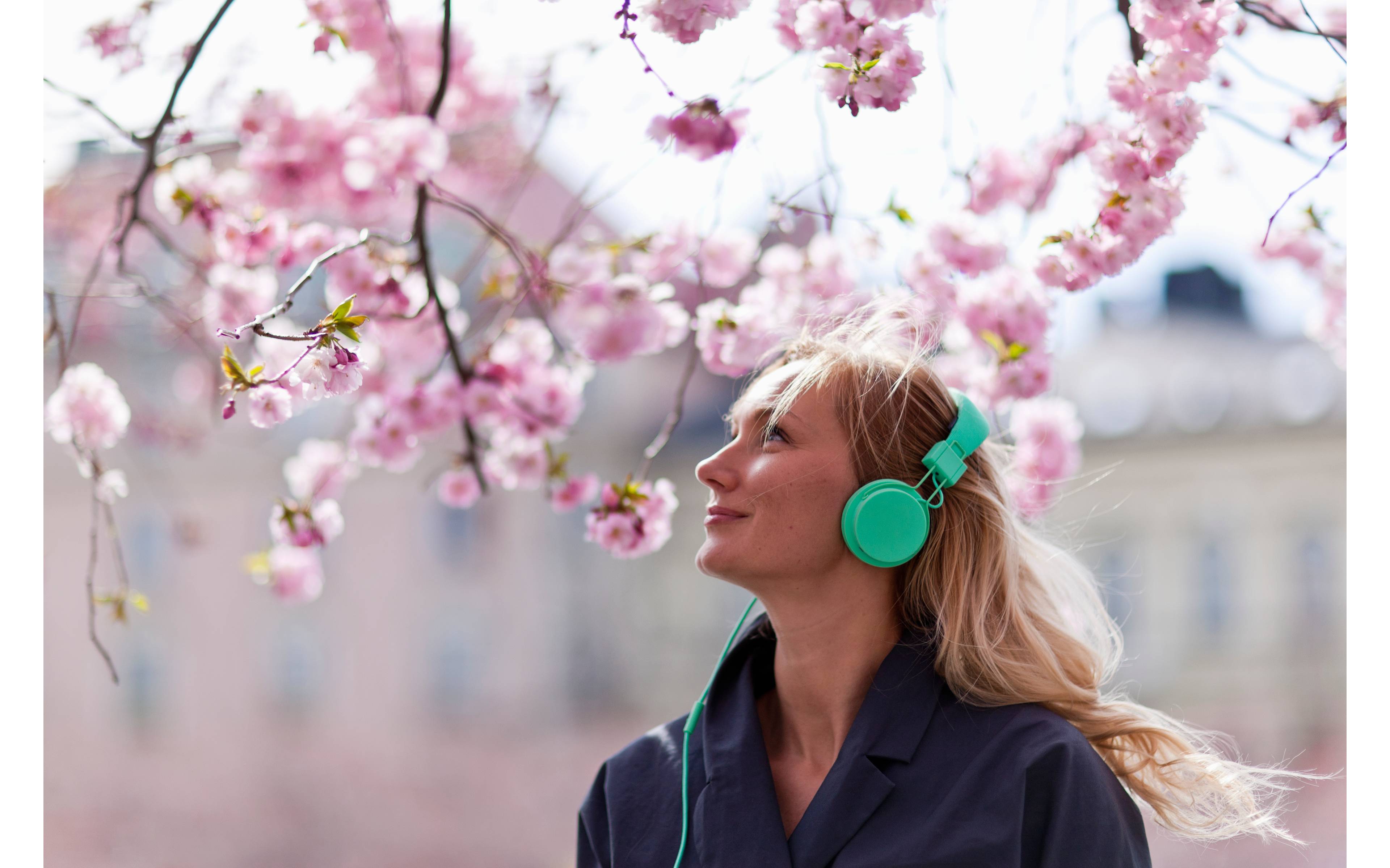 Kvinne med høretelefoner under et kirsebærtre