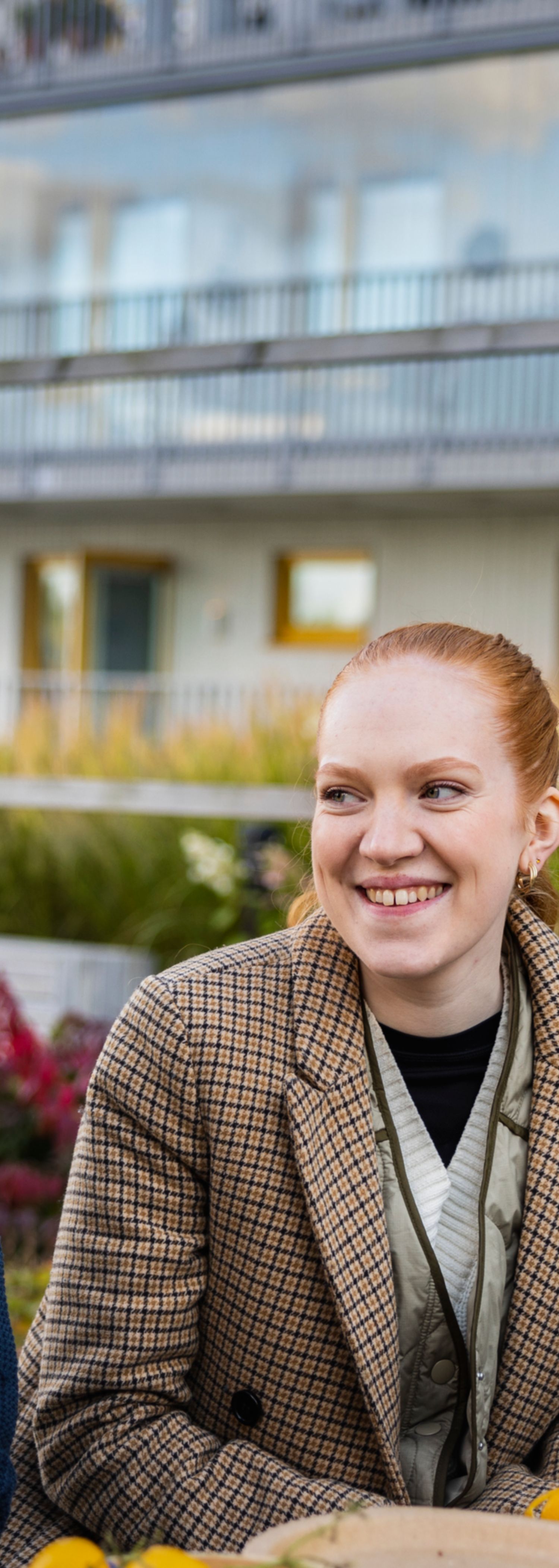 Ung kvinne og eldre mann prater ved et bord i en bakgård