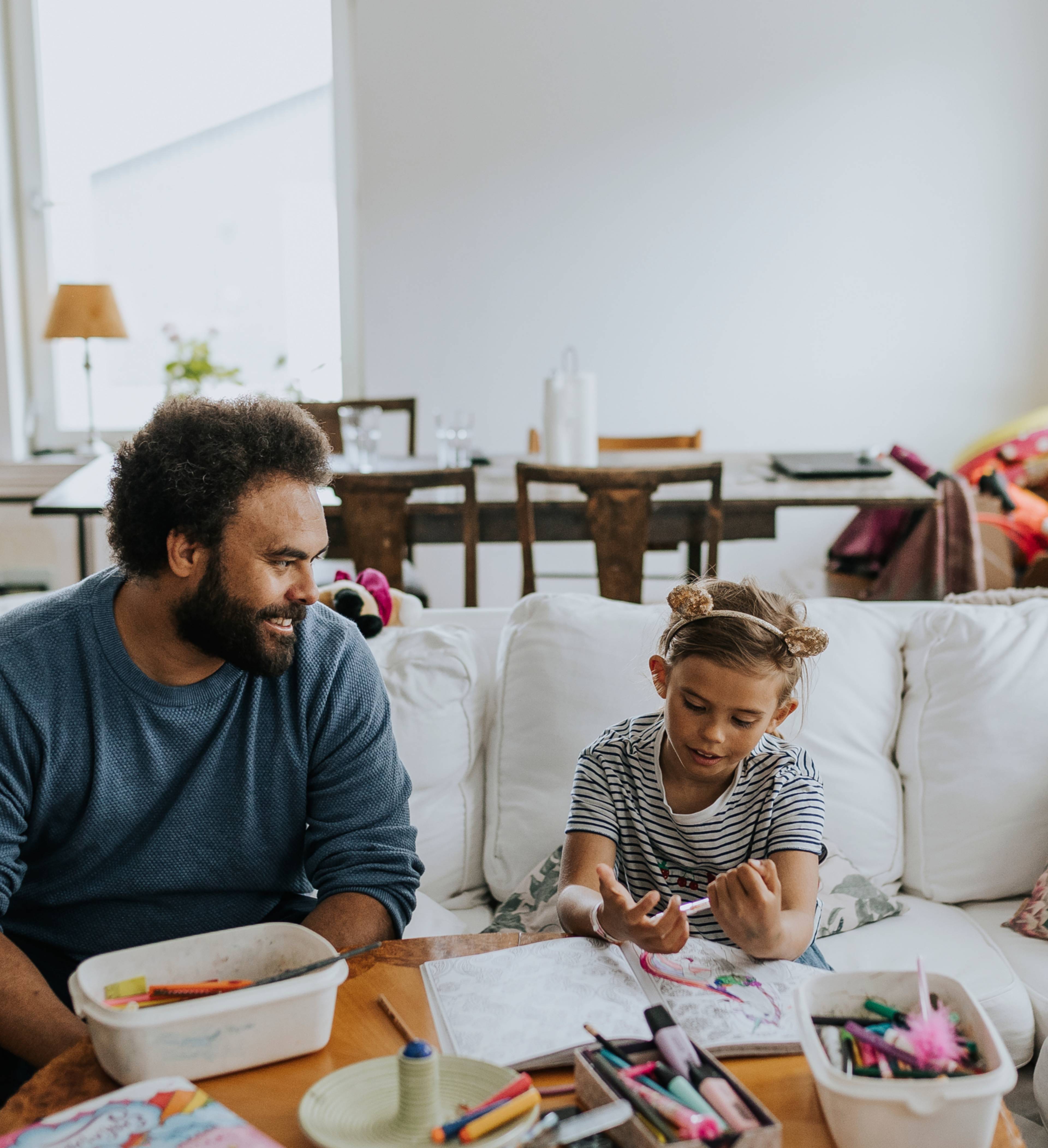 Far og datter tegner sammen i stuen