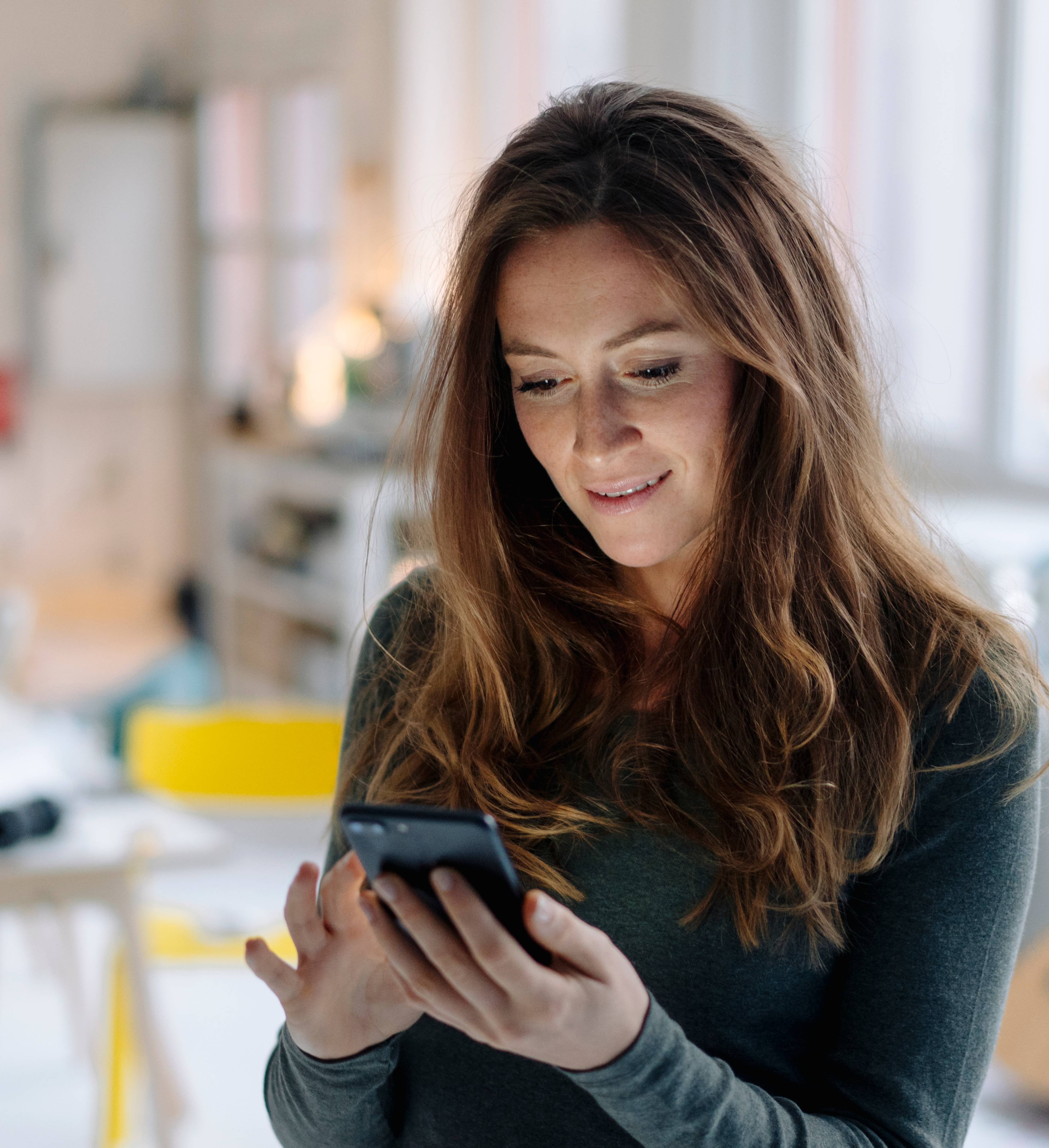 Kvinne med mobiltelefon i stuen