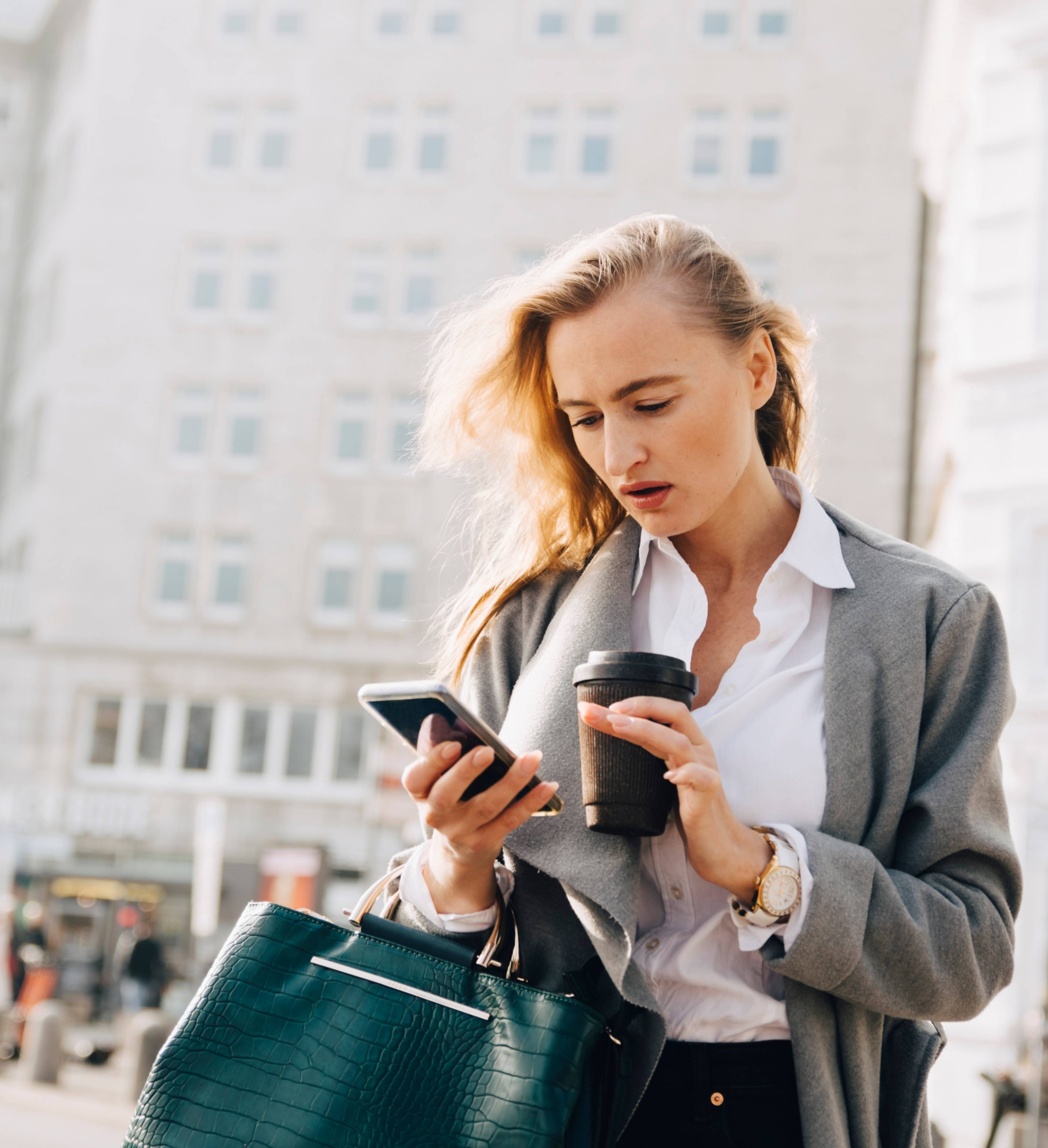 Kvinne sjekker telefonen på torg