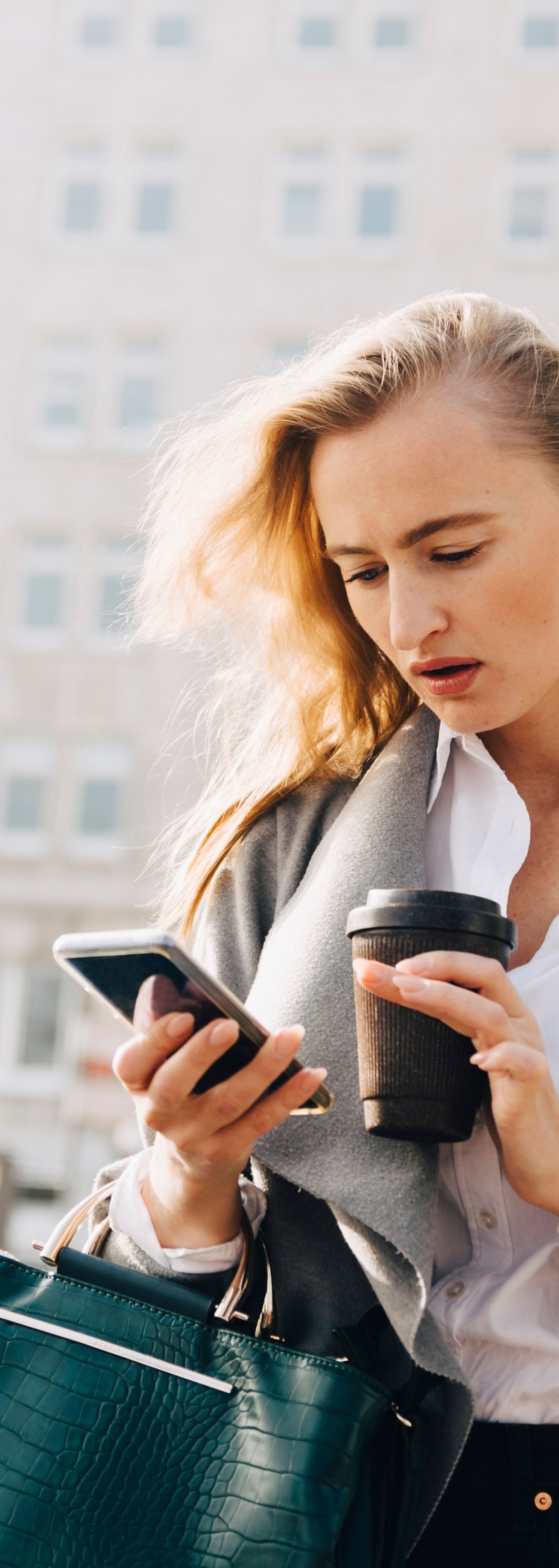 Kvinne sjekker telefonen på torg