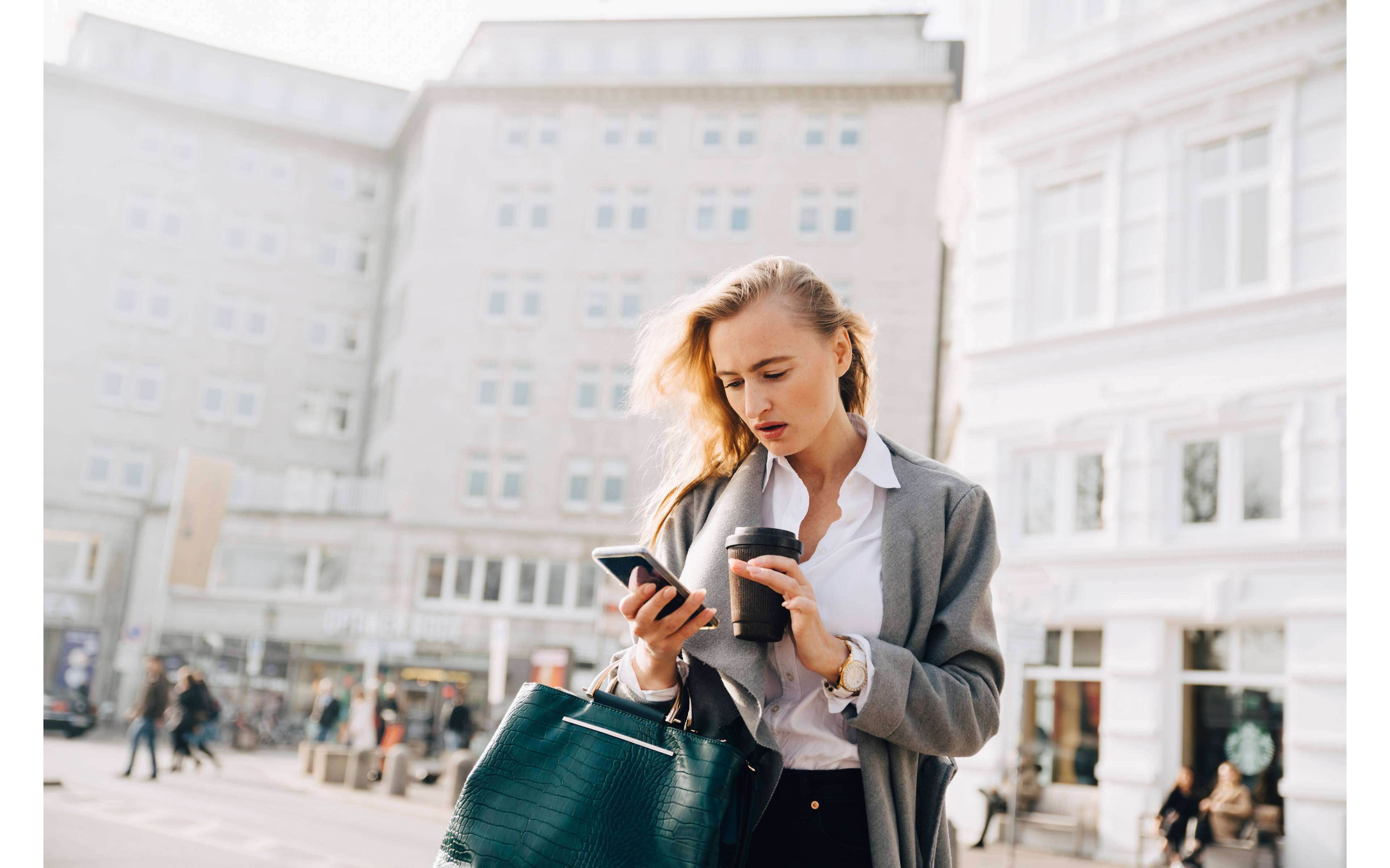 Kvinne sjekker telefonen på torg