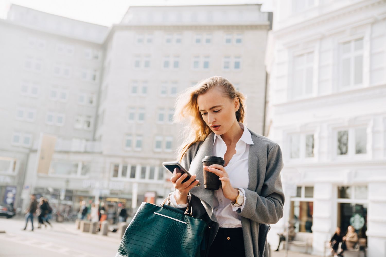 Kvinne sjekker telefonen på torg