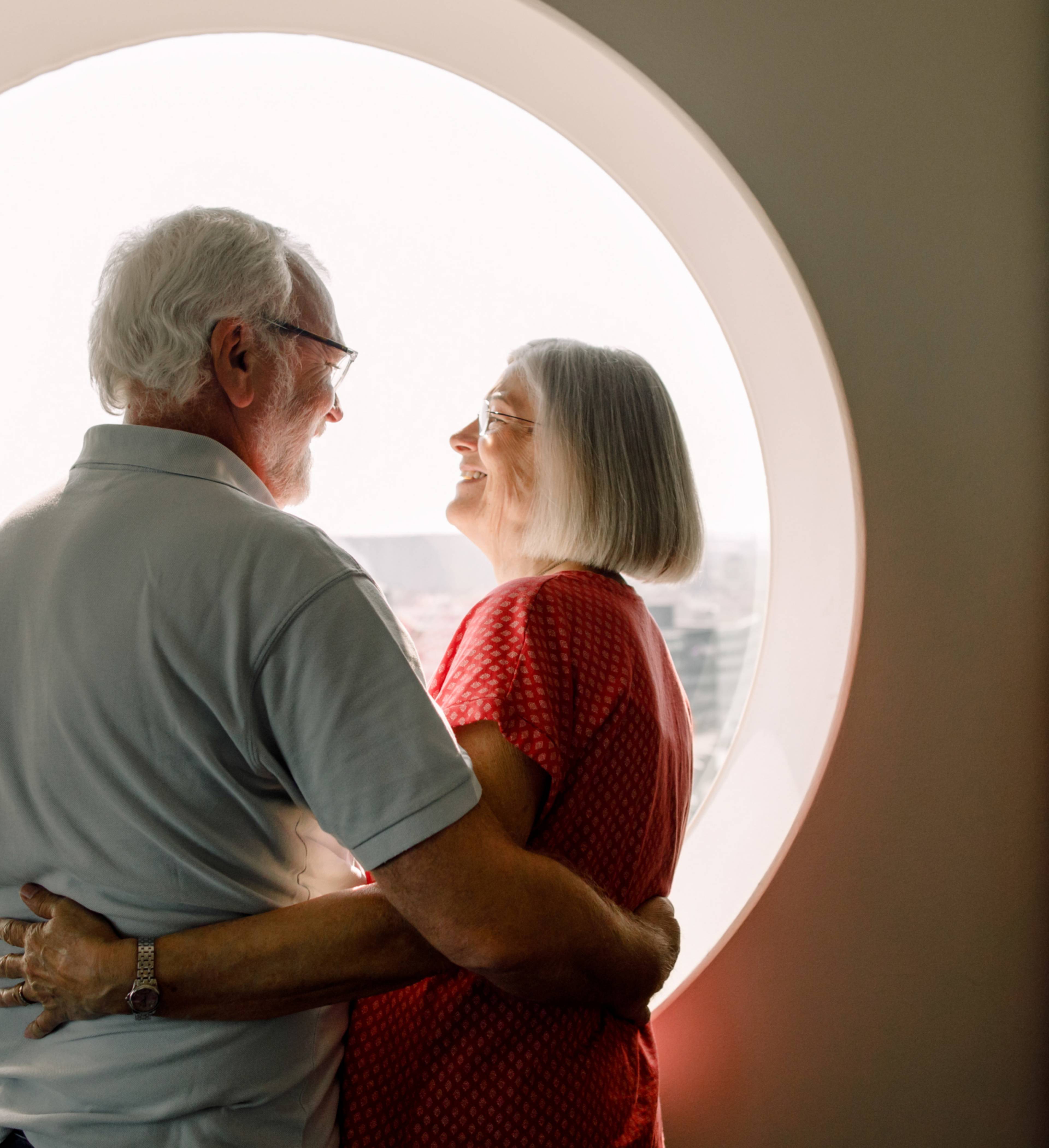 Eldre par holder rundt hverandre foran vindu