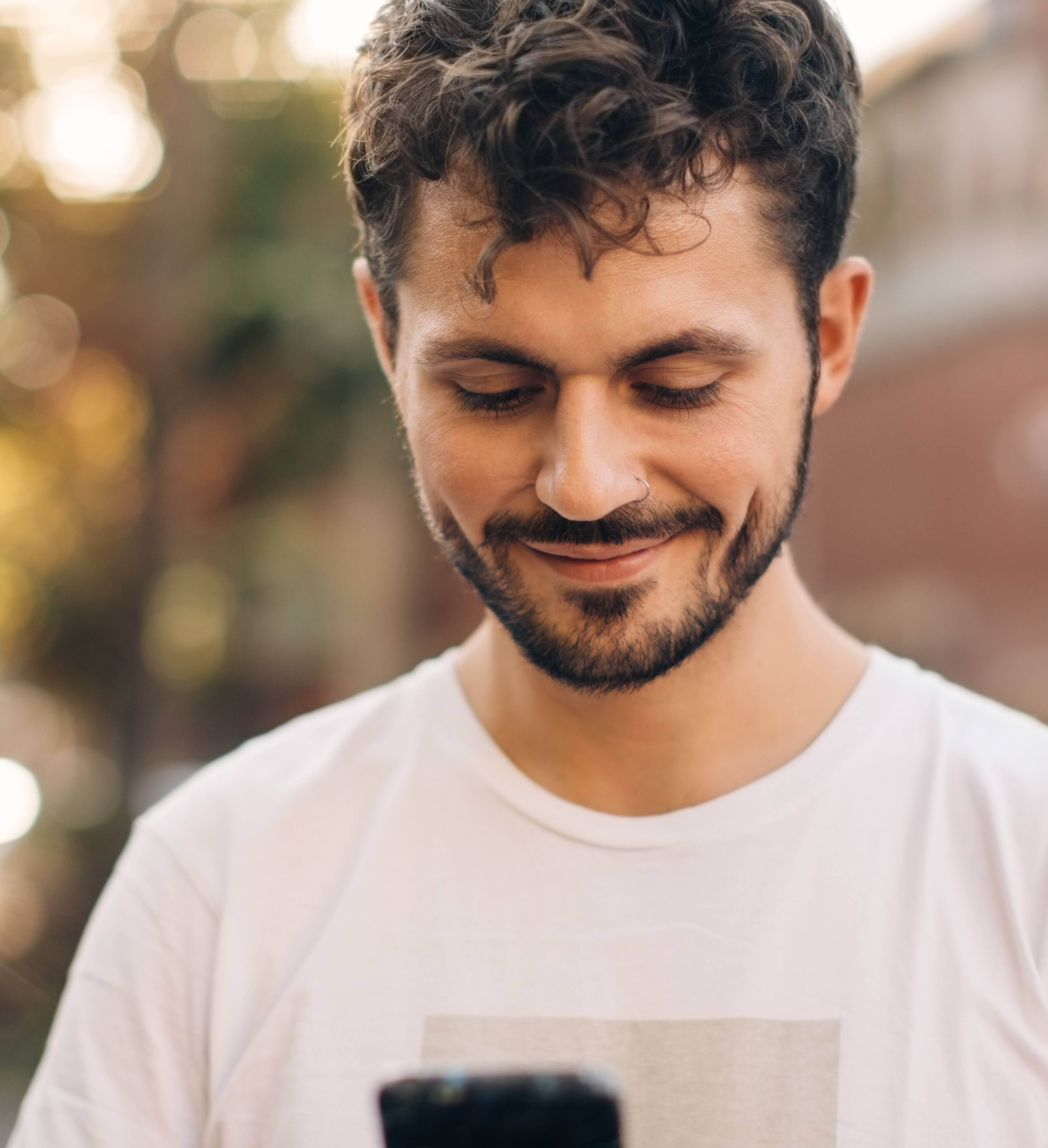 Smilende mann ser på mobilen
