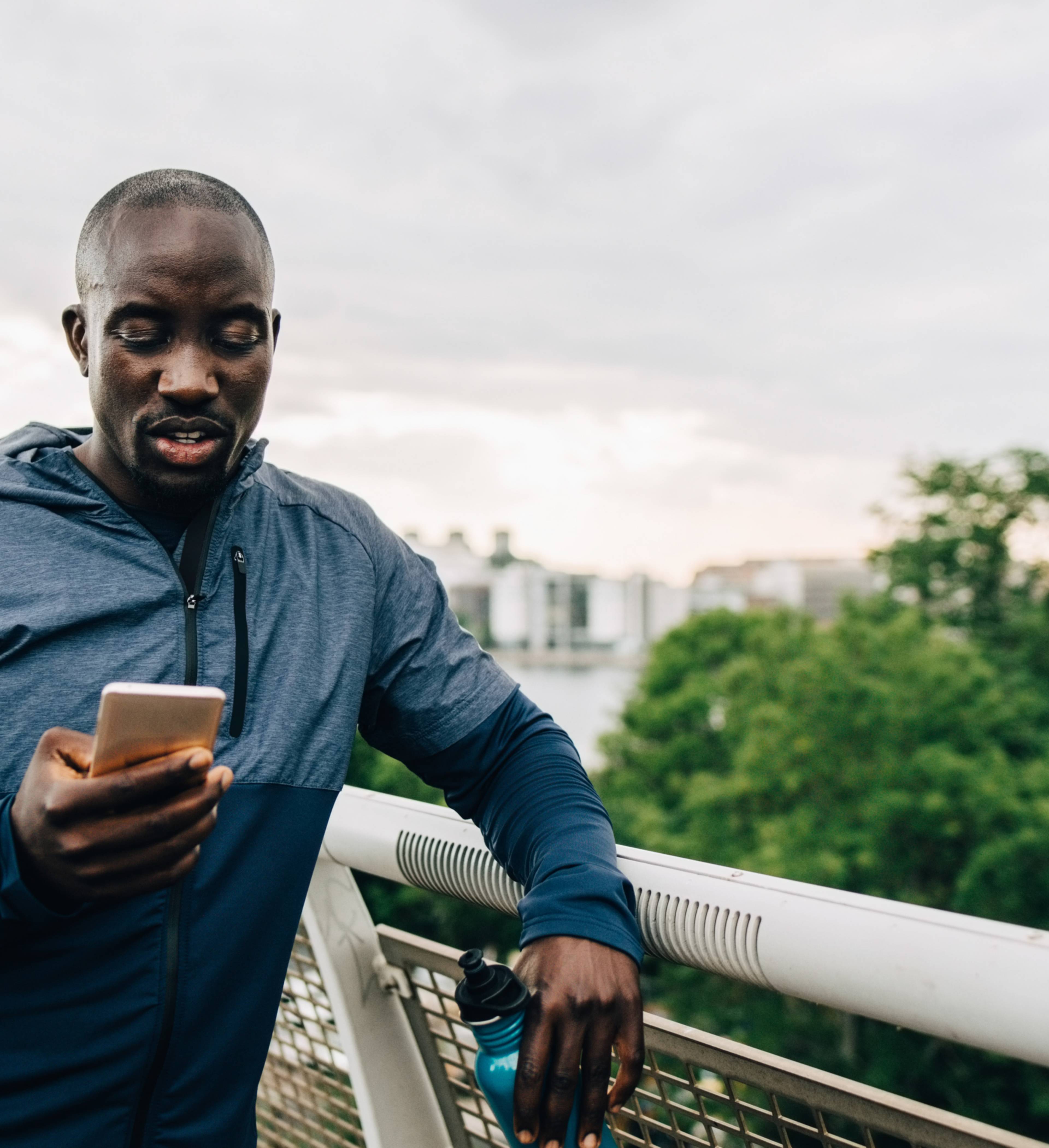 Mann står i treningstøy og ser på mobilen