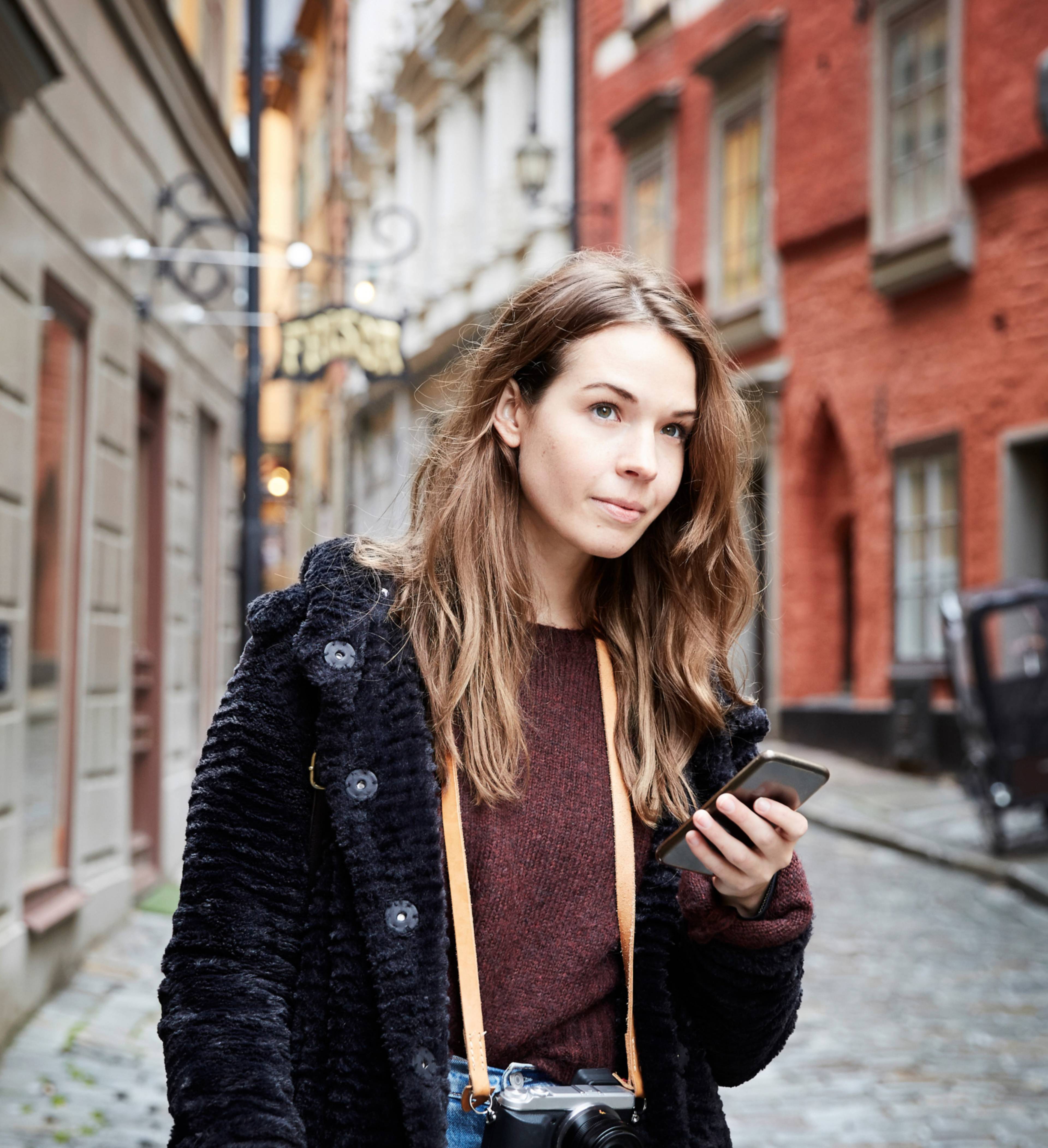 Ung kvinne i byen med kamera rundt halsen