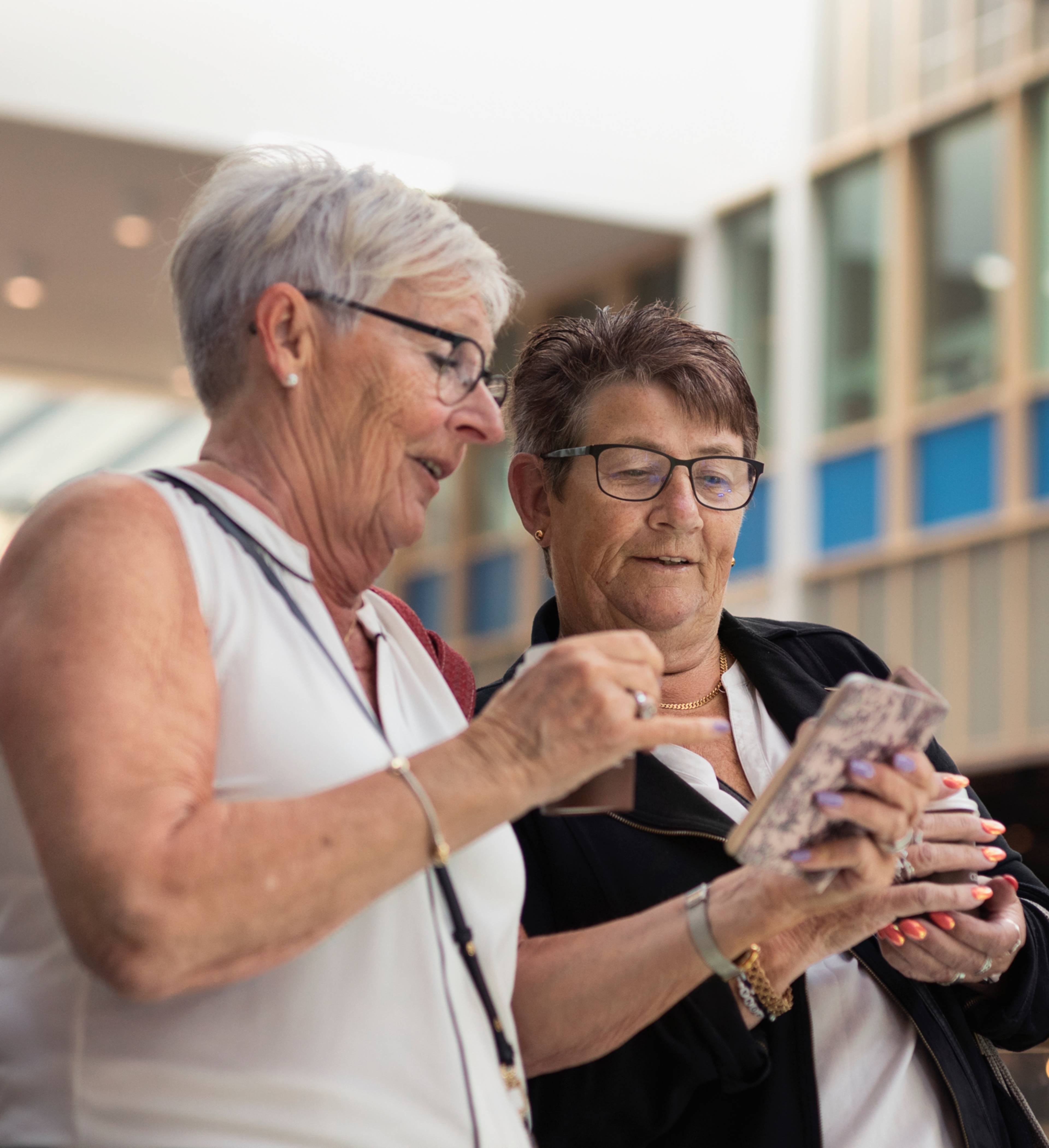 Eldre damer ser på mobil sammen