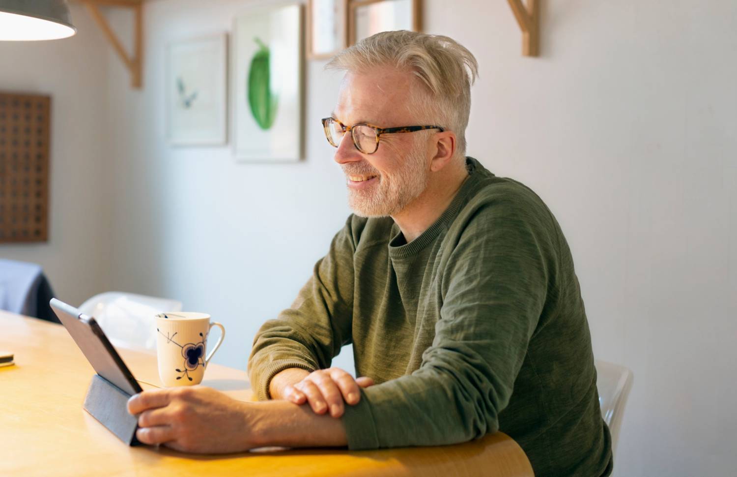 Mann sitter ved spisebordet med nettbrett