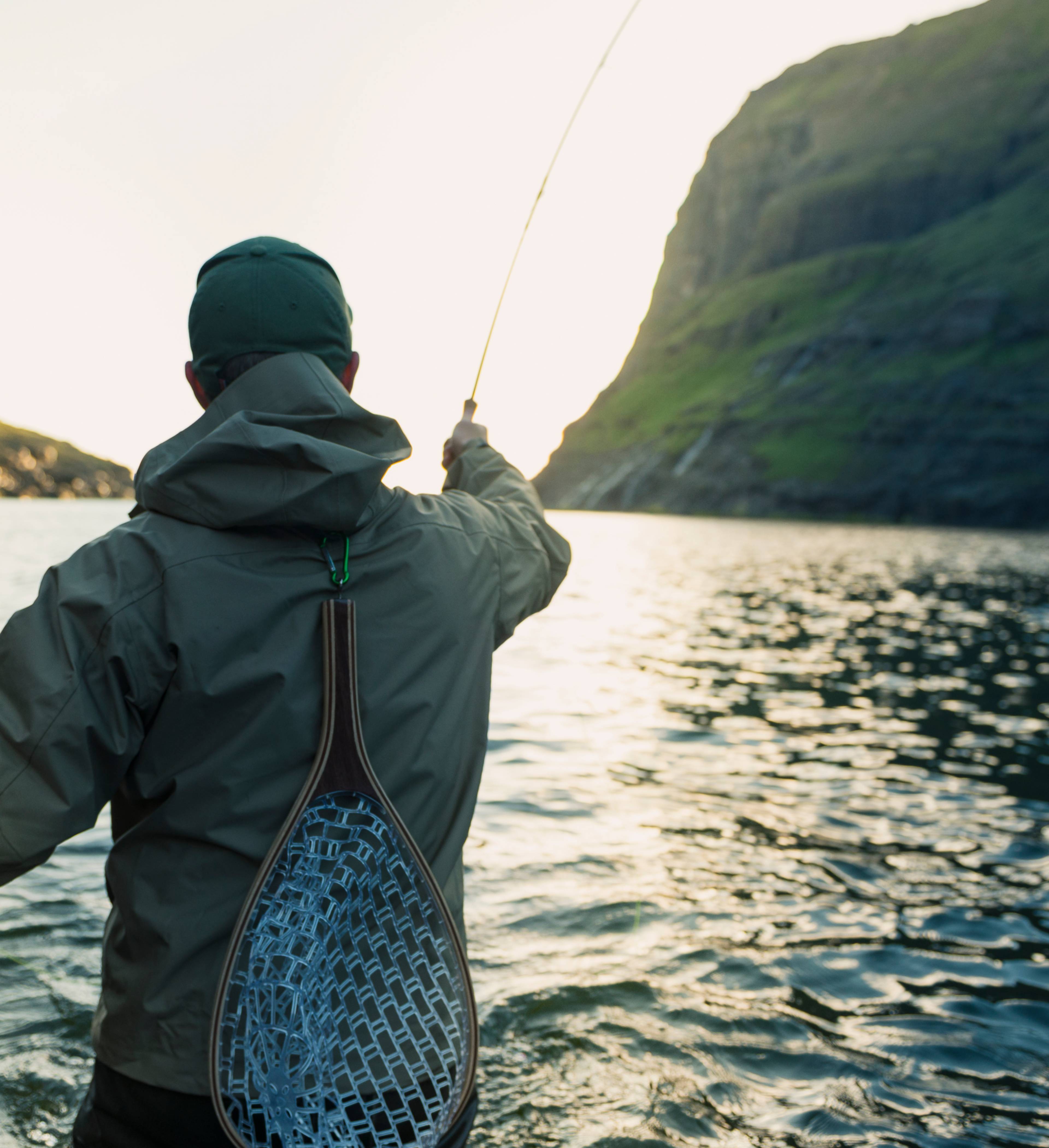 Mann står i vann og fisker