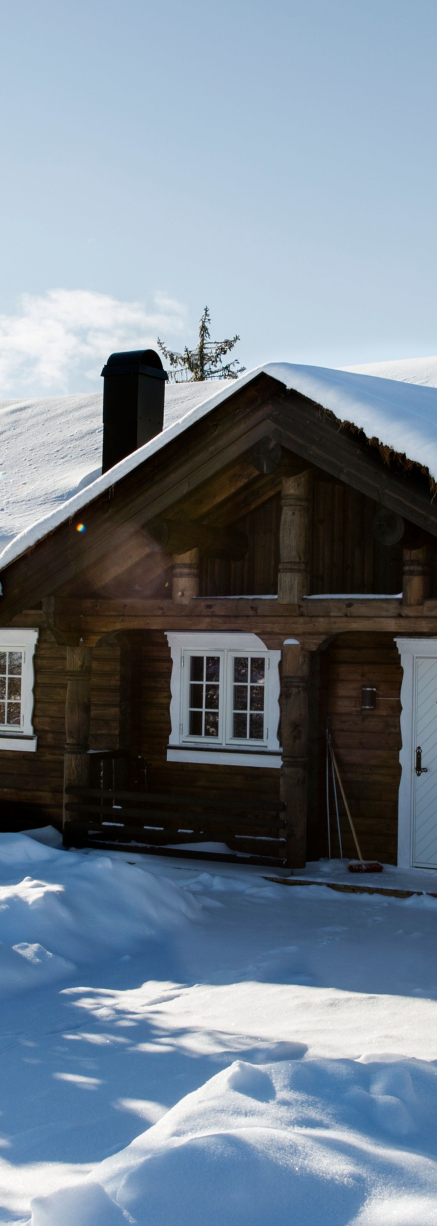 Hytte dekket i snø med bil utenfor