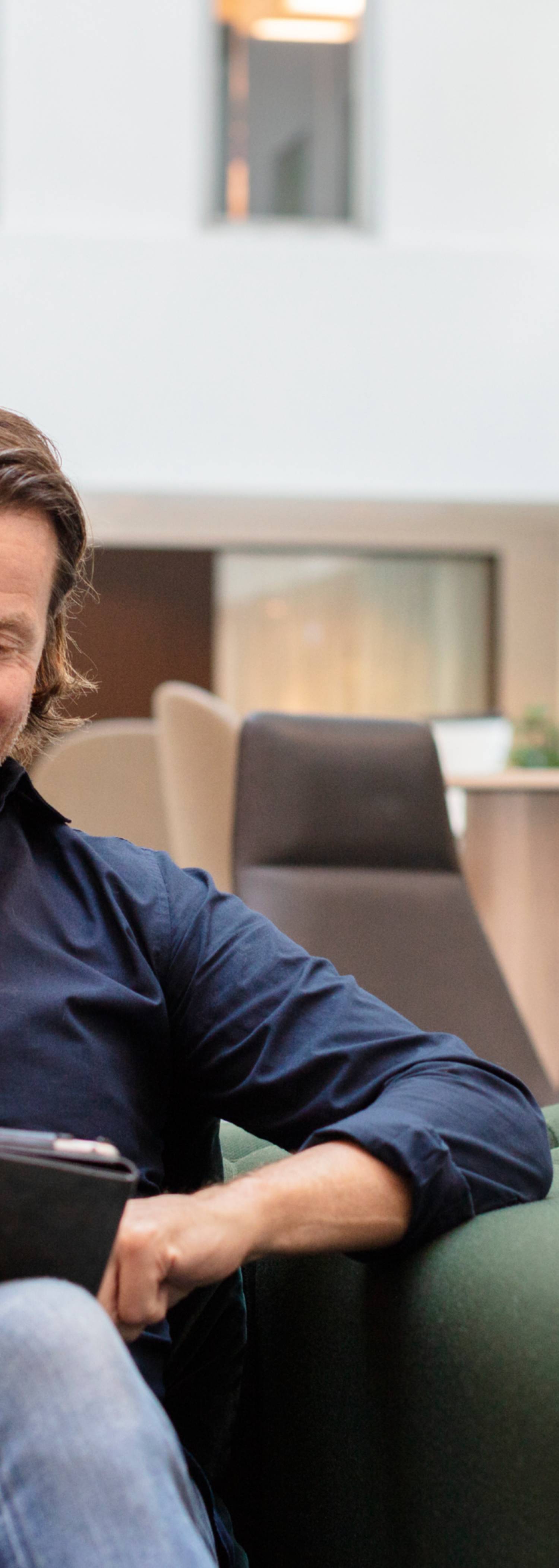 Man smiler og ser på nettbrett
