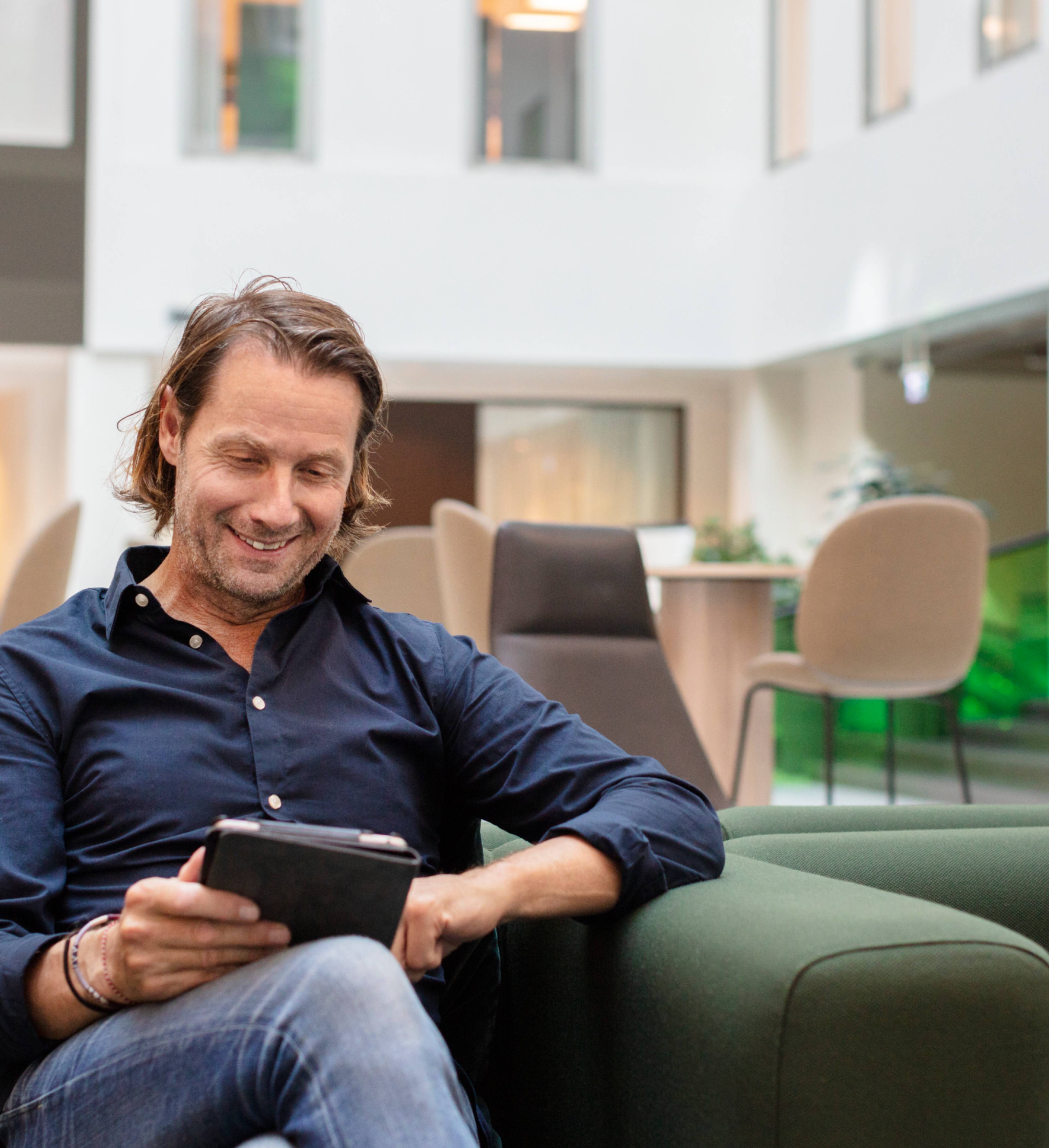 Man smiler og ser på nettbrett