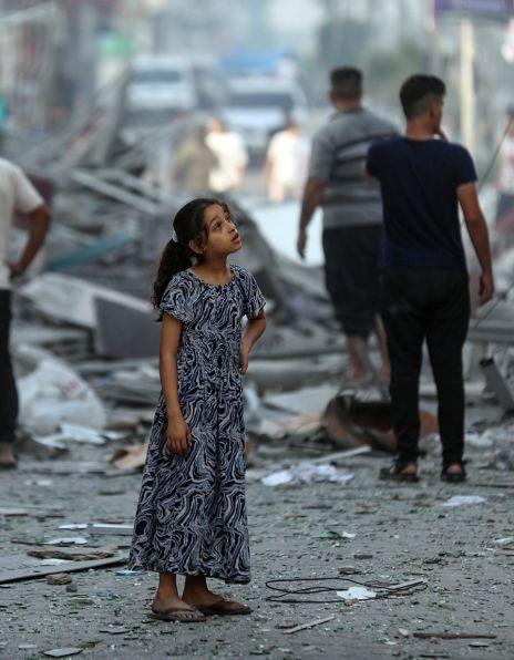 Fortvilet jente som står og ser rundt et ødelagt nabolag