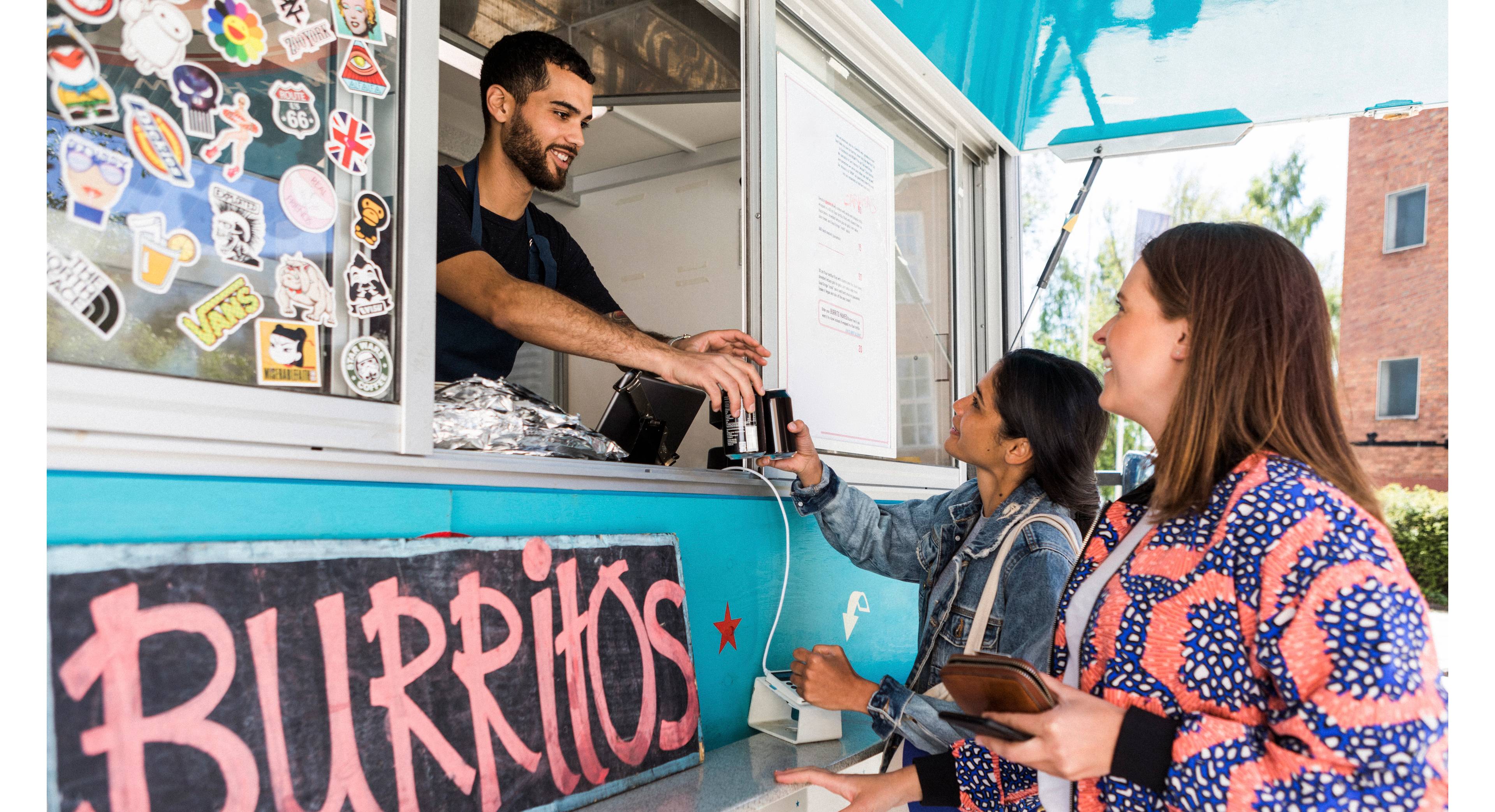Smilende kvinner kjøper noe fra en foodtruck BRUKE