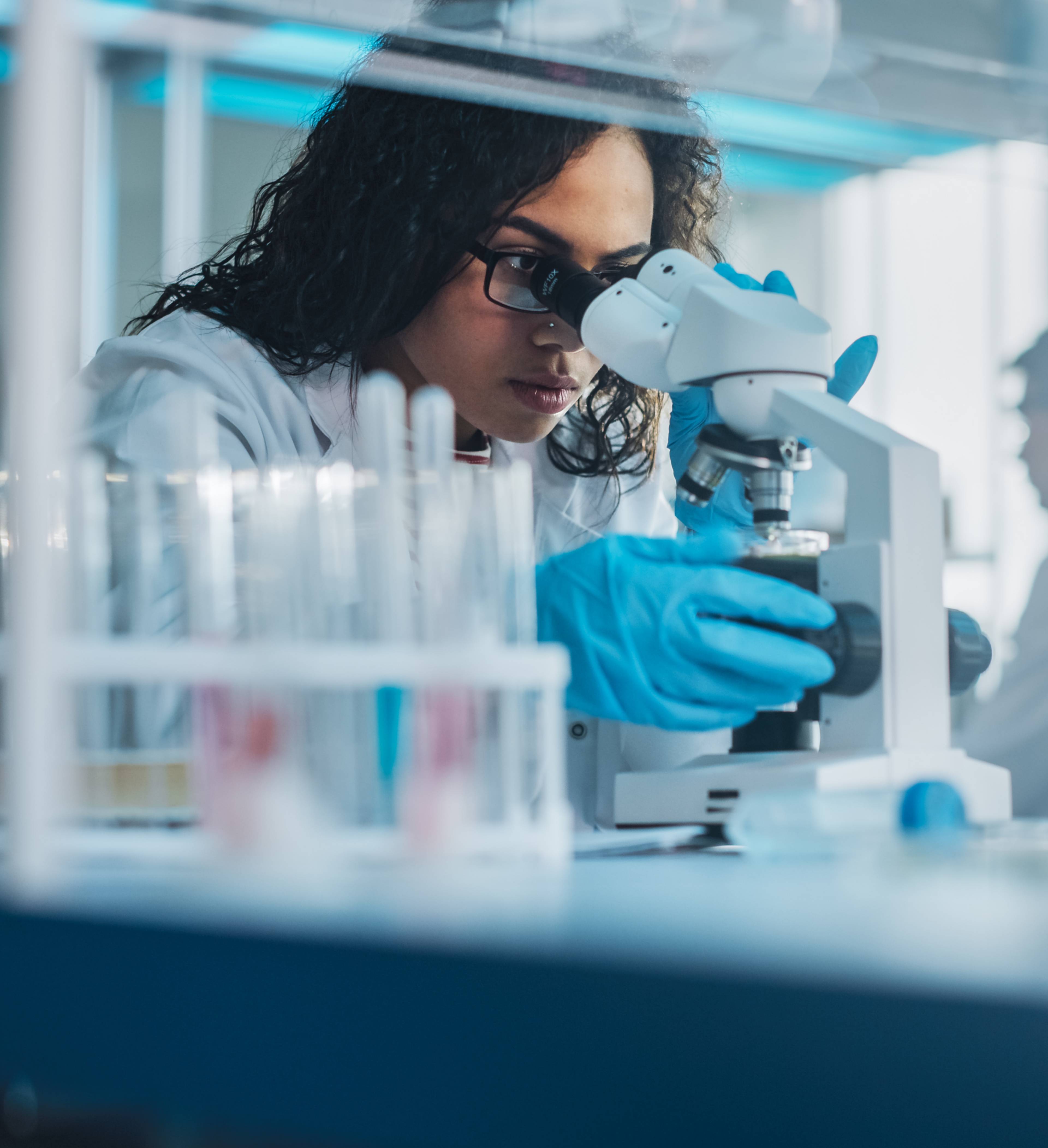 Dame studerer i mikroskop på lab