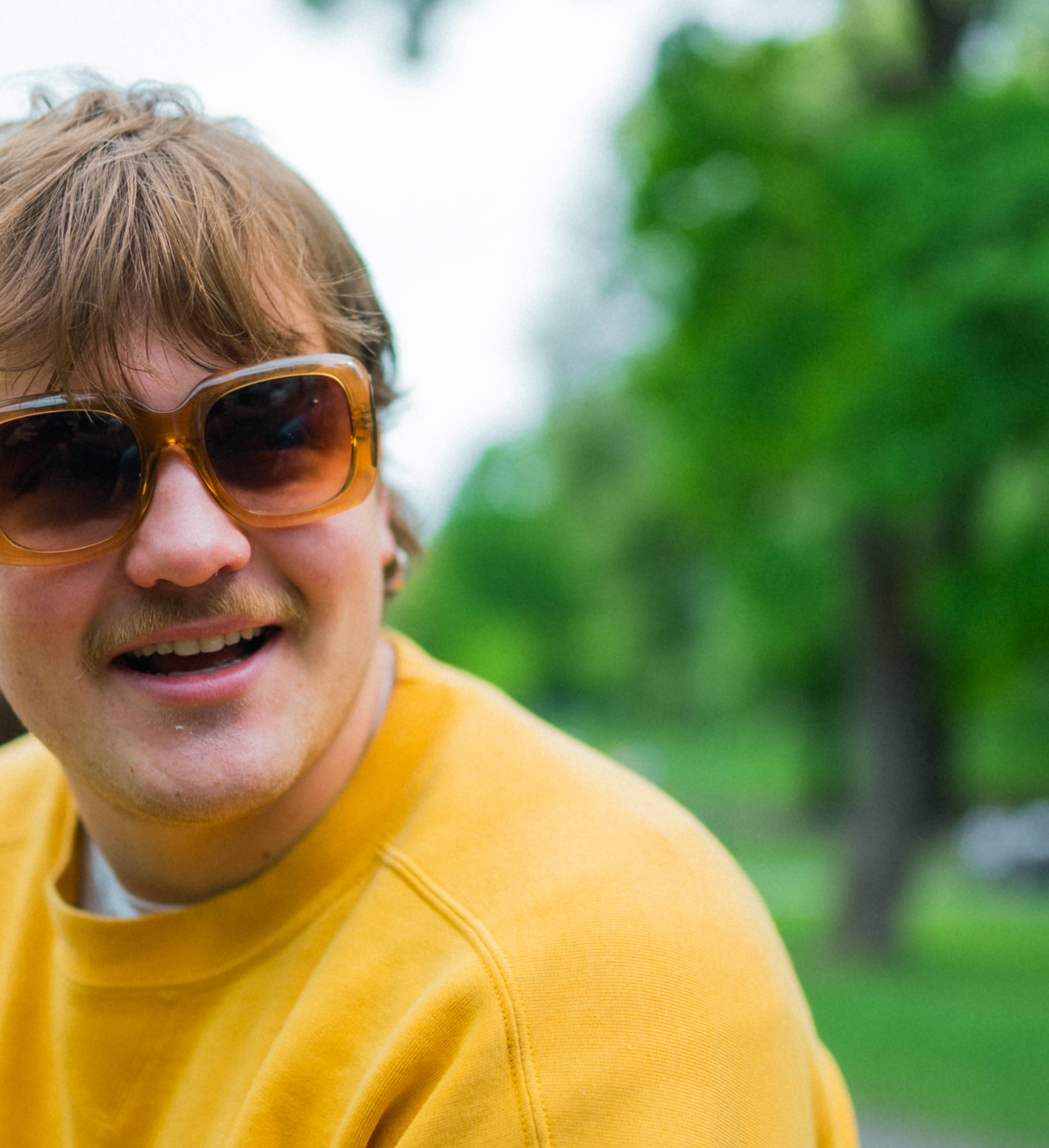 Smilende ung mann med solbriller i parken