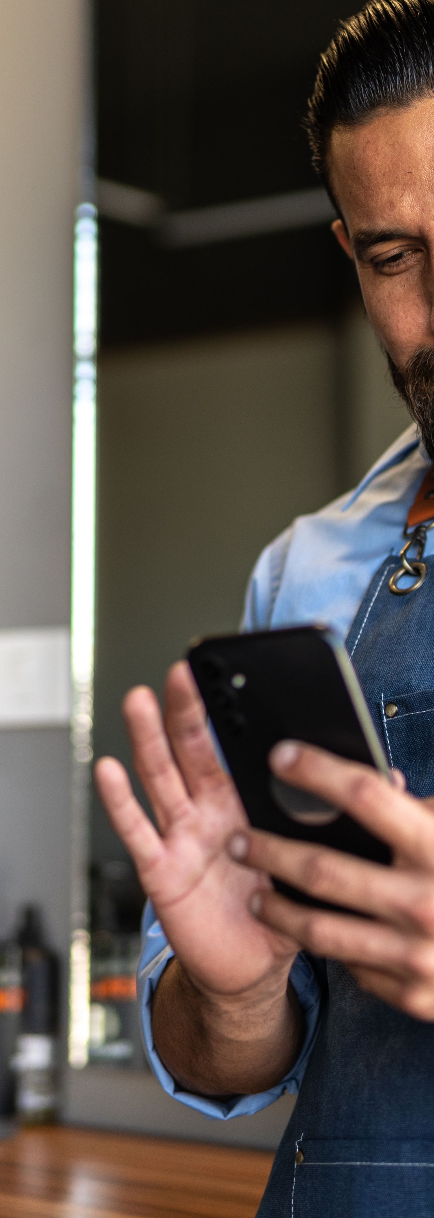 Frisør sjekker mobilen i frisørsalong