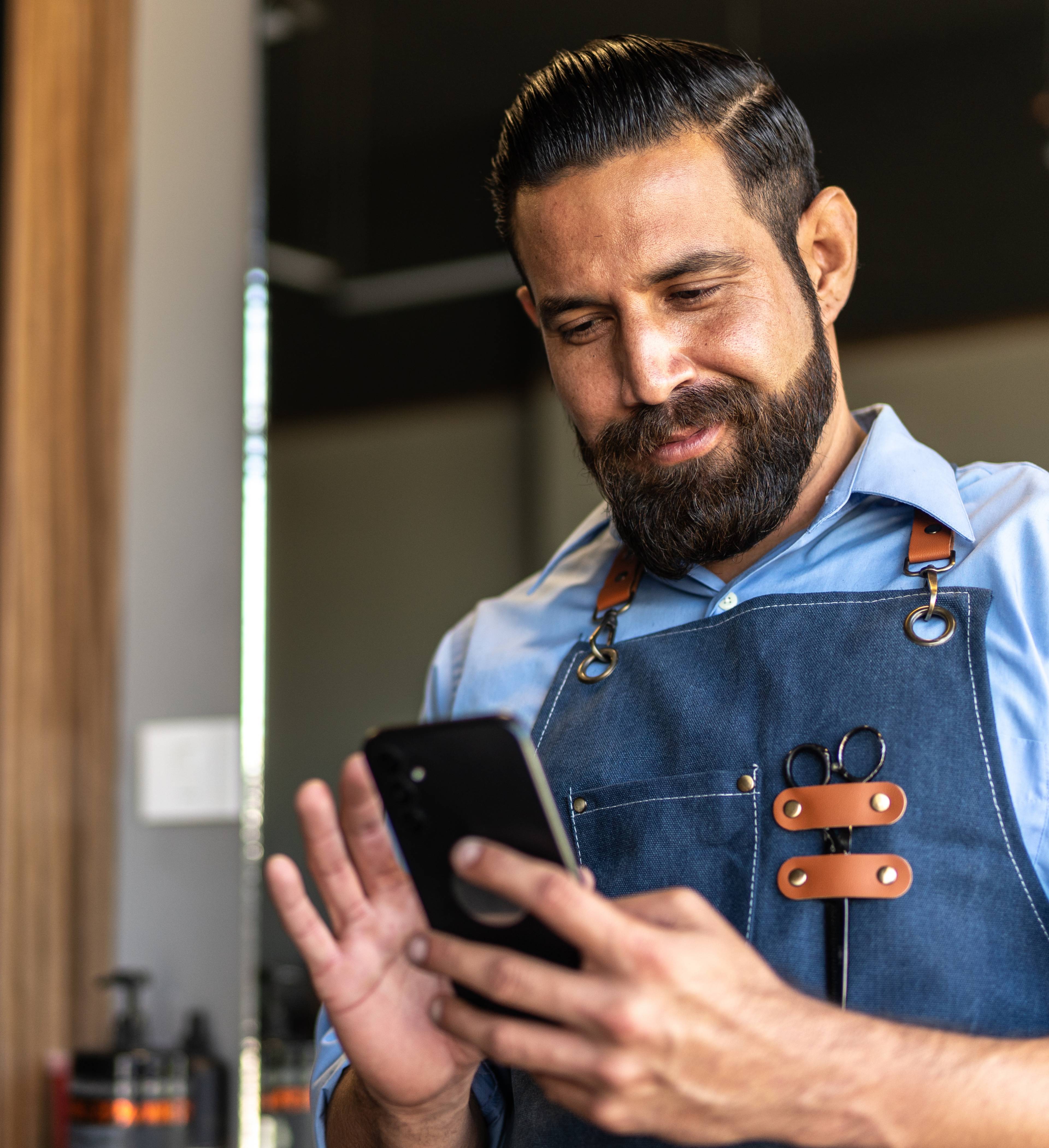 Hairdresser checks his cell phone in the hairdresser salon