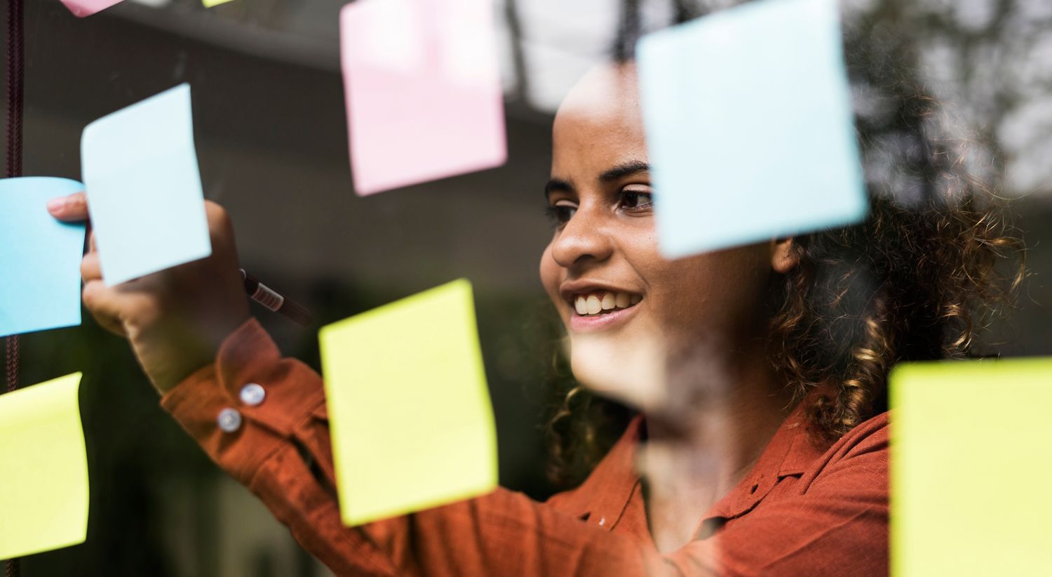 Woman hanging up Post-it notes. Photo.